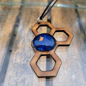 The Bohemian necklace features a unique Zen figure made of wood and fused blue g